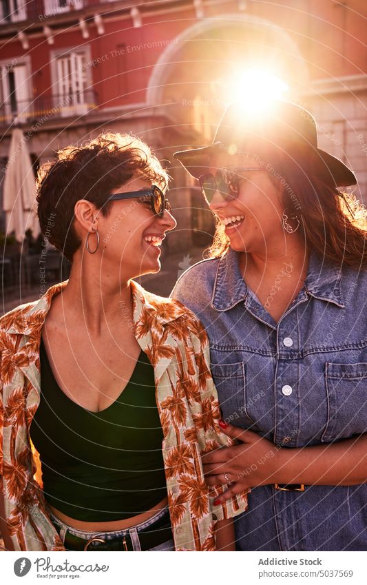 Glad couple hugging against sunset light on street women smile girlfriend together happy love Plaza Mayor madrid spain female young sunlight twilight sunglasses