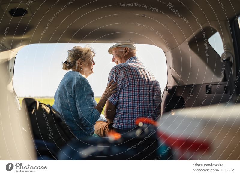 Happy senior couple sitting in car open trunk in the wild journey transportation auto road road trip travel adventure holiday woman two people mature together