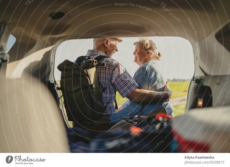 Happy senior couple sitting in car open trunk in the wild journey transportation auto road road trip travel adventure holiday woman two people mature together