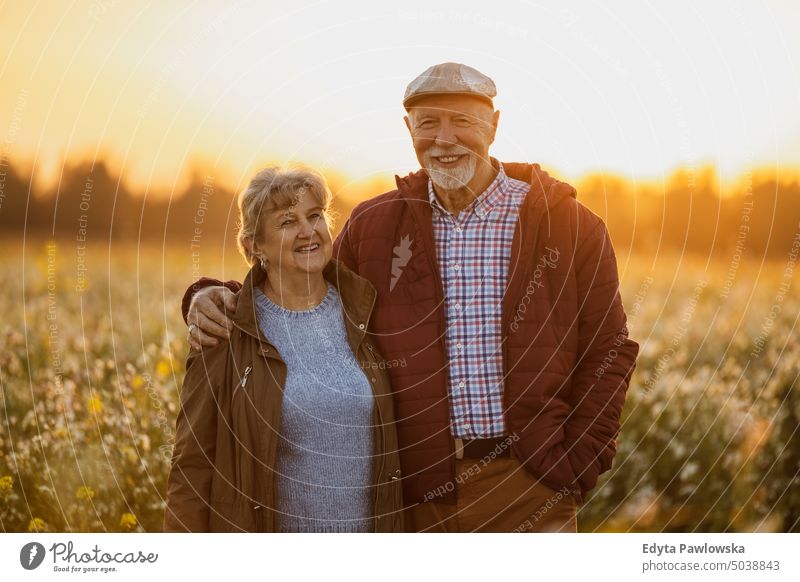 Senior couple in a field in autumn at sunset walking trip backpack senior couple woman two people mature together old retired joy love happiness adult female