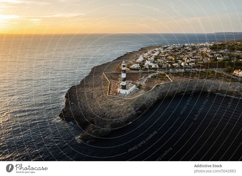 Scenic rocky cliff with lighthouse near settlement sea Spain menorca beacon landscape seascape city green sundown sunset scenic building water breathtaking