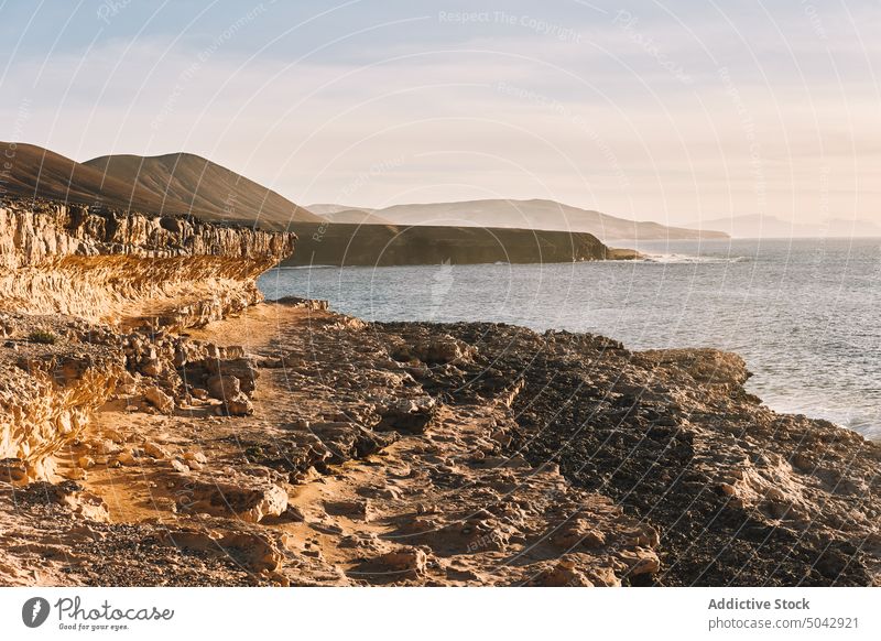 Rocky cliff and rippling sea under sundown sky ocean sunset landscape seascape breathtaking rocky island nature picturesque mountain scenic fuerteventura coast