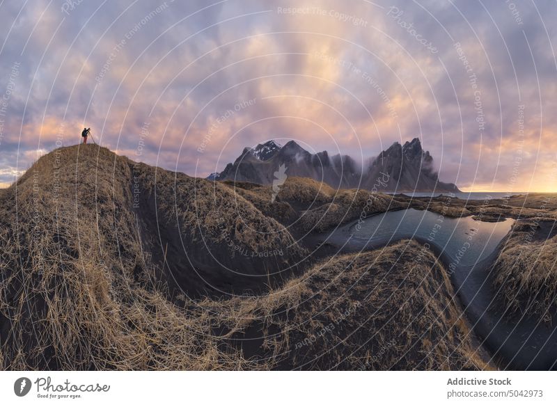 Traveler standing on top of mountain in winter stockness beach iceland vestrahorn traveler picturesque landscape adventure black sand dry glass breathtaking sky