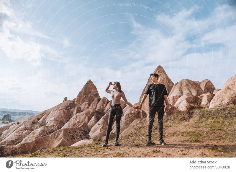 Young stylish couple holding hands and enjoying view of fairy chimneys cliff admire trip together travel vacation wanderlust mountain hoodoo boyfriend