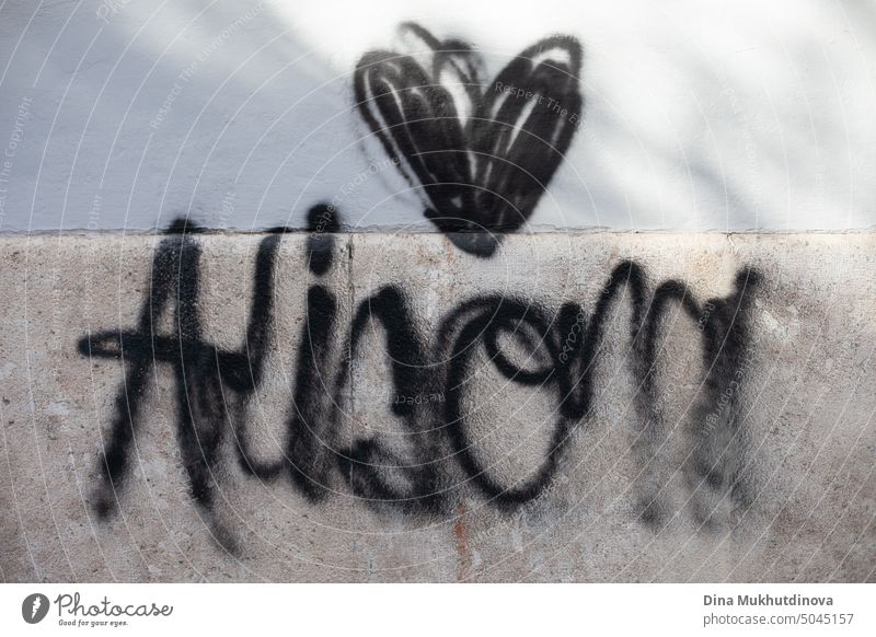 Graffiti painted with black paint on the wall. Black heart spray painted on the stone wall of building. Urban street art. artistic anarchy graffiti symbol