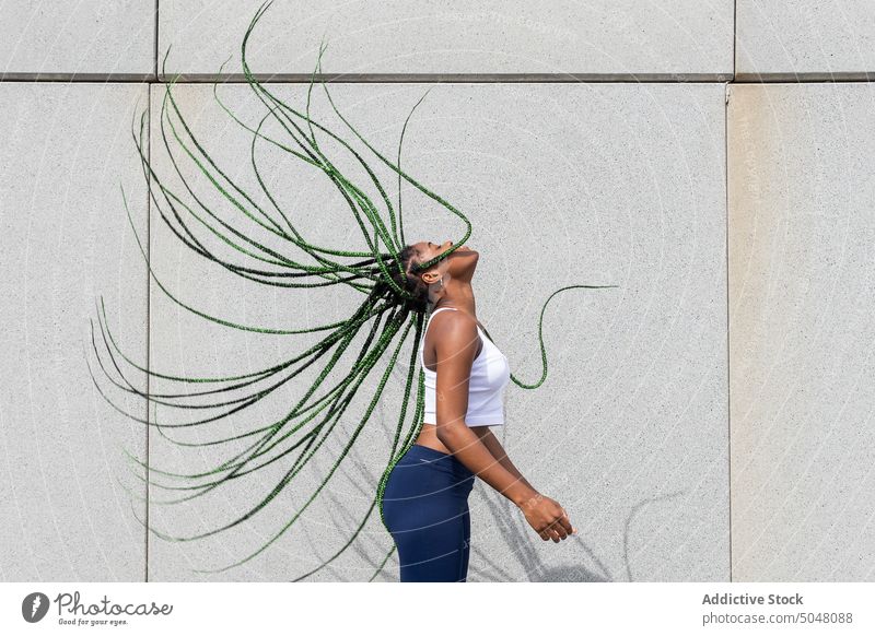 Energetic woman shaking hair in dance street style urban cool flying hair long hair town millennial individuality contemporary generation personality