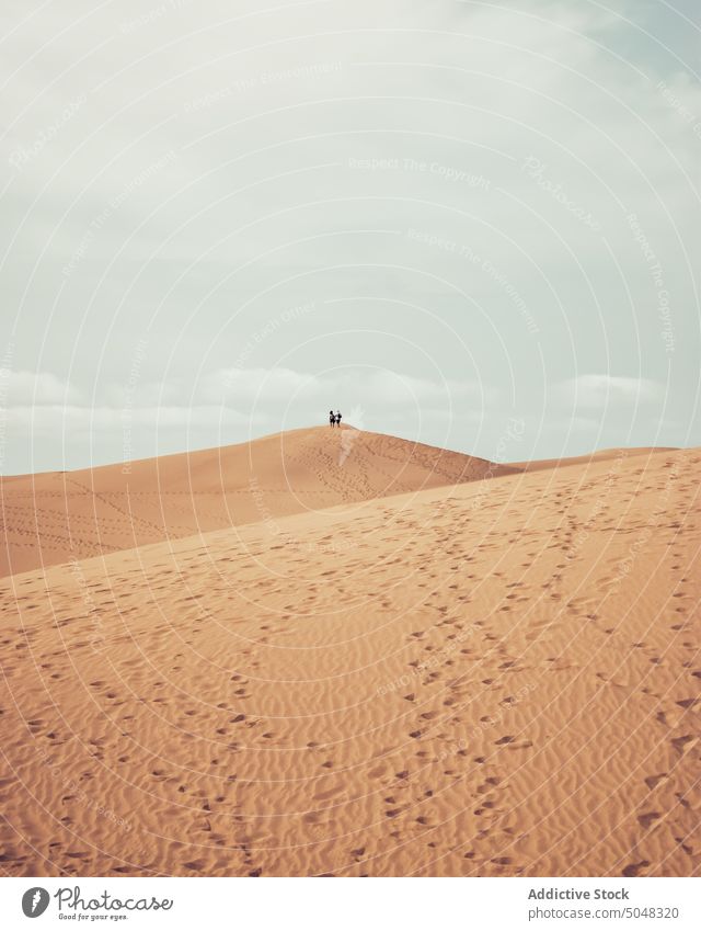 People walking on sand dune people cloudy sky traveler seashore beach vacation maspalomas gran canaria canary islands spain tourism trip tourist desert