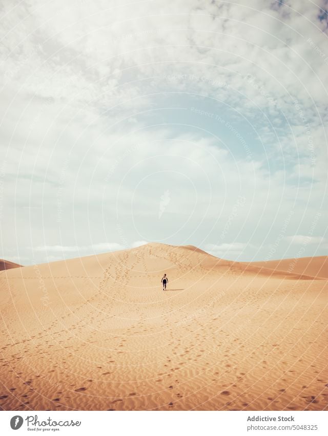 Anonymous woman walking on dune desert admire beach tourist explore blue sky sand maspalomas gran canaria canary islands spain weekend observe traveler vacation