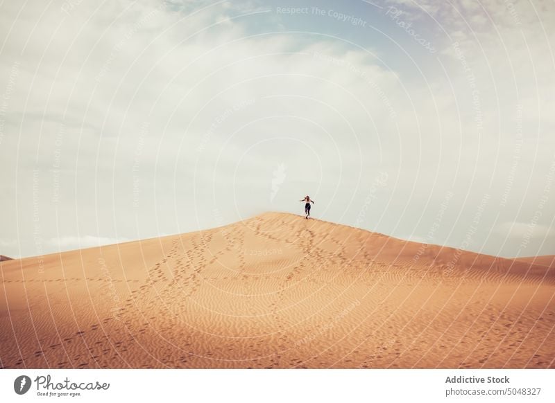 Woman running on sand dune woman sky cloudy freedom traveler hill weekend maspalomas gran canaria canary islands spain desert tourism wanderlust seashore