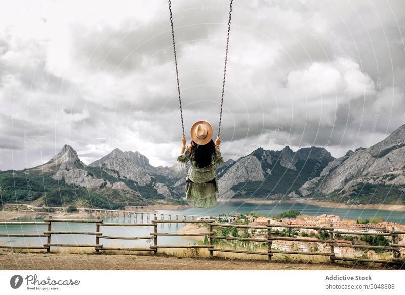 Anonymous woman on swing near mountain lake town Leon tourist Riano spain weekend cloudy sky romantic female brunette rock coast ridge range shore highland