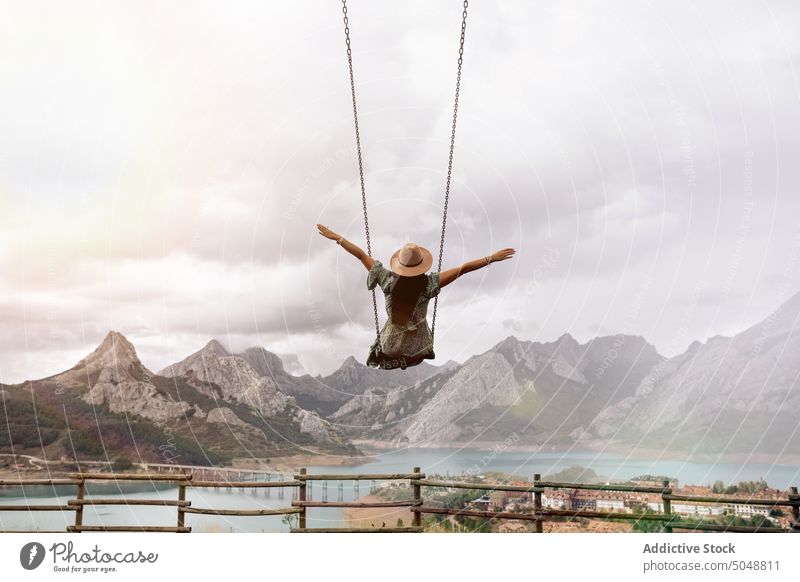 Anonymous woman on swing near mountain lake town Leon tourist Riano spain weekend cloudy sky romantic female brunette rock coast ridge range shore highland