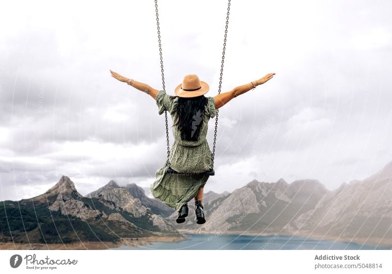 Anonymous woman on swing near mountain lake town Leon tourist Riano spain weekend cloudy sky romantic female brunette rock coast ridge range shore highland