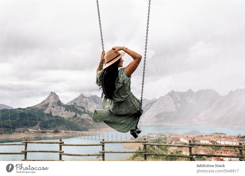 Anonymous woman on swing near mountain lake town Leon tourist Riano spain weekend cloudy sky romantic female brunette rock coast ridge range shore highland