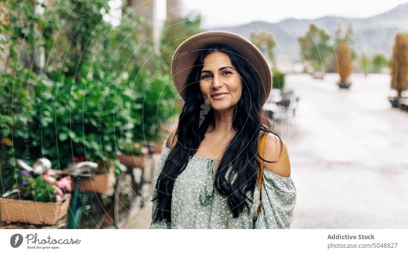 Happy woman on town square traveler mountain smile happy summer weekend portrait female adult tourist vacation tourism holiday sunhat long hair black hair