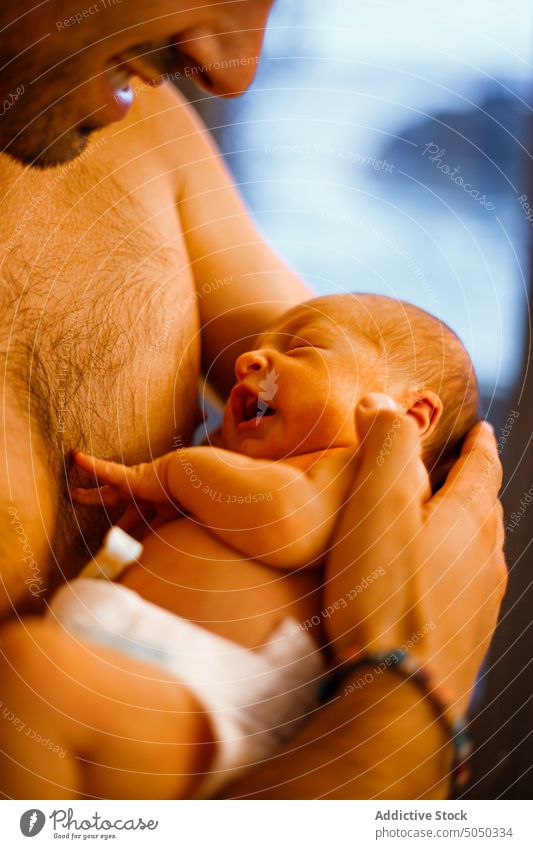 Shirtless man holding newborn baby in arms father infant love care gentle parenthood happy home diaper tender childhood together bonding cute smile adorable