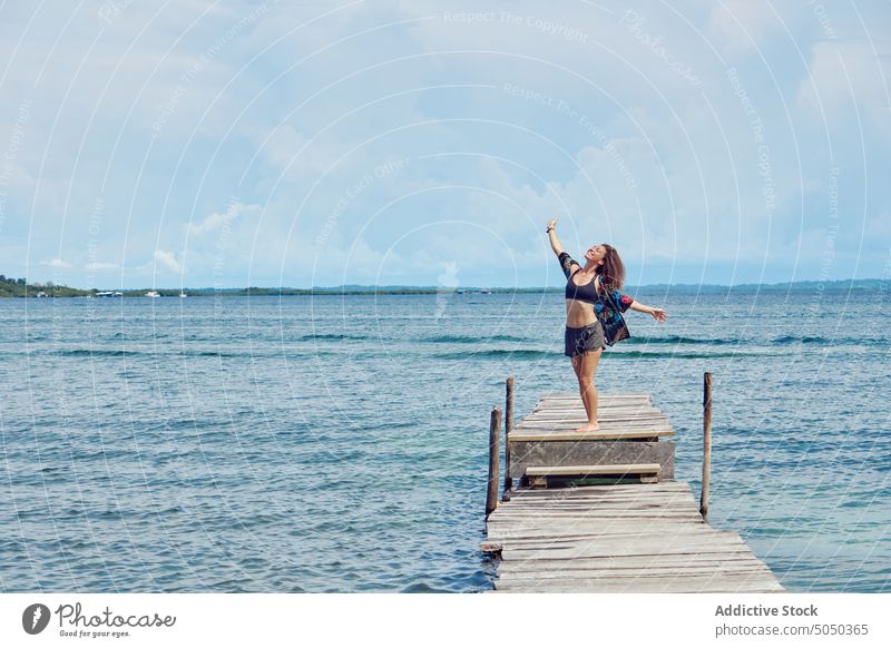 Happy woman standing on pier of sea freedom enjoy relax happy alone carefree seascape summer vacation nature seashore sunlight serene calm tranquil long hair