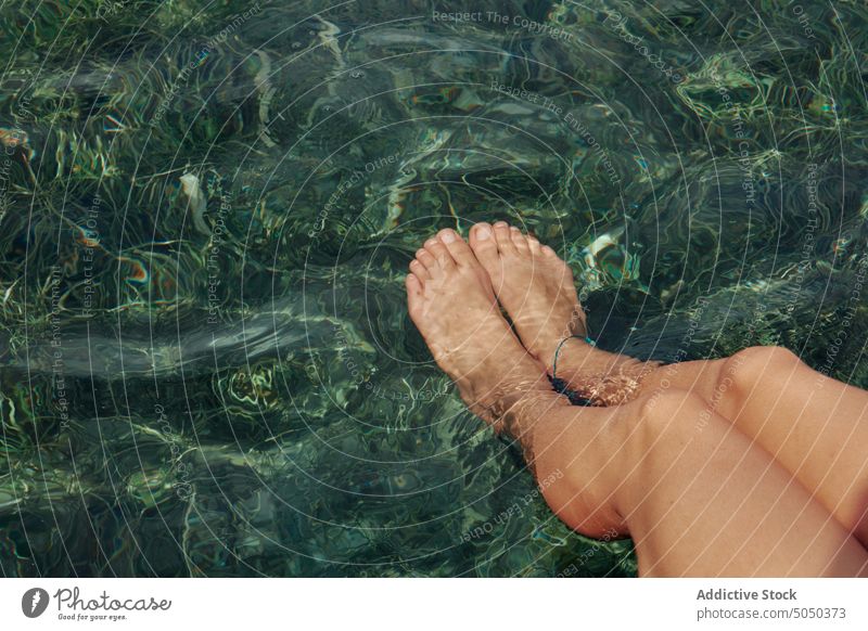 Anonymous relaxed woman dangling legs in water from pier summer tropical rest carefree shabby peaceful serene sea nature calm foot enjoy harmony holiday sit