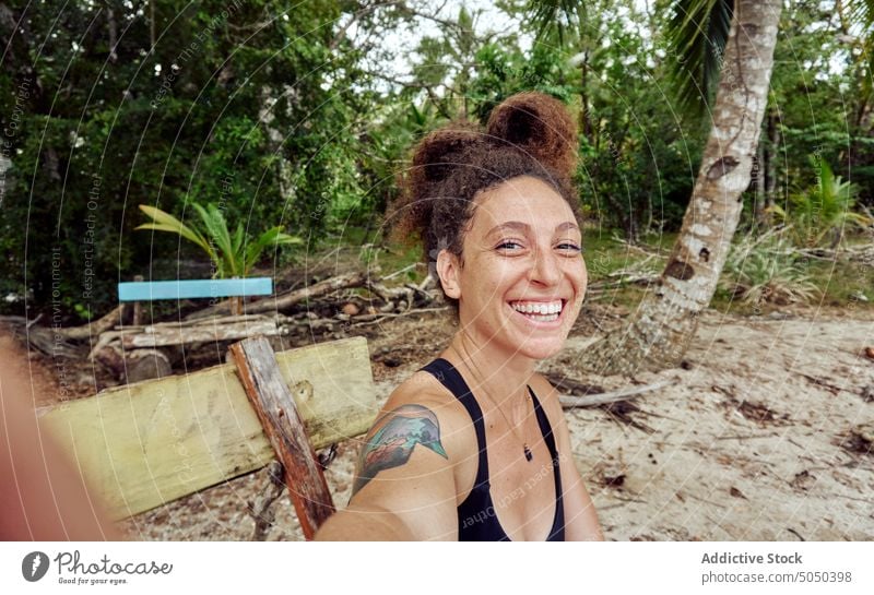 Happy woman taking selfie on bench on tropical shore cheerful beach seashore happy holiday summer exotic smile resort palm ethnic hispanic positive vacation