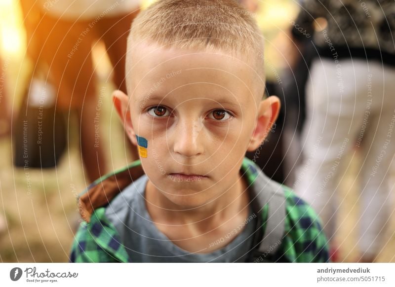 close up of smiling child with painted Ukrainian flag on face. Protest against Russian war invasion in Ukraine. Ukrainian Flag, Protesters concept conflict