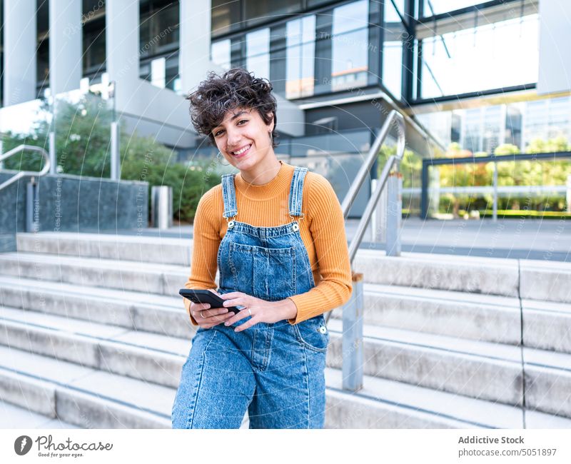 Woman using mobile phone on street woman smartphone browsing cellphone summer urban style city female brunette rail connection porch railing hispanic ethnic