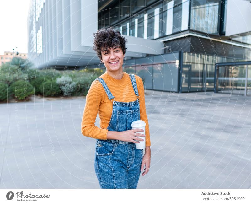 Carefree lady walking against contemporary building woman street summer carefree enjoy urban female pillar cheerful free time style city smile positive brunette