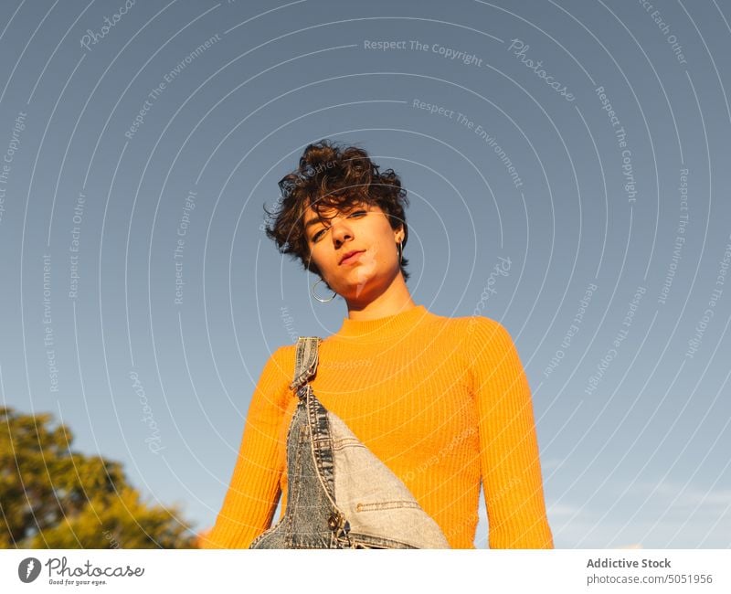 Pensive woman standing on sunny street thoughtful pensive calm sunlight casual shadow urban personality female alone short hair serious individuality building