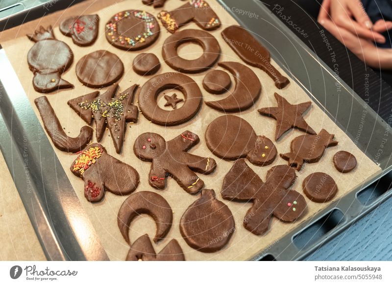 Christmas and New Year cookies of different shapes in the process of decoration with a multi-colored sprinkling on a baking sheet gingerbread cookies sweets