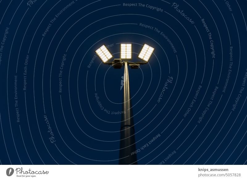 A floodlight system at night. A switched on floodlight mast at night. Floodlight Light pole Floodlit game Lighting Sporting grounds sports facility Stadium