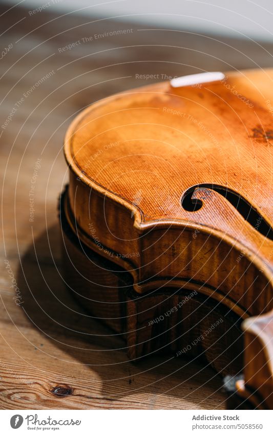 Hand crafted wooden violin on workbench workshop instrument luthiery table artisan shiny maker production handicraft manufacture professional handmade polished