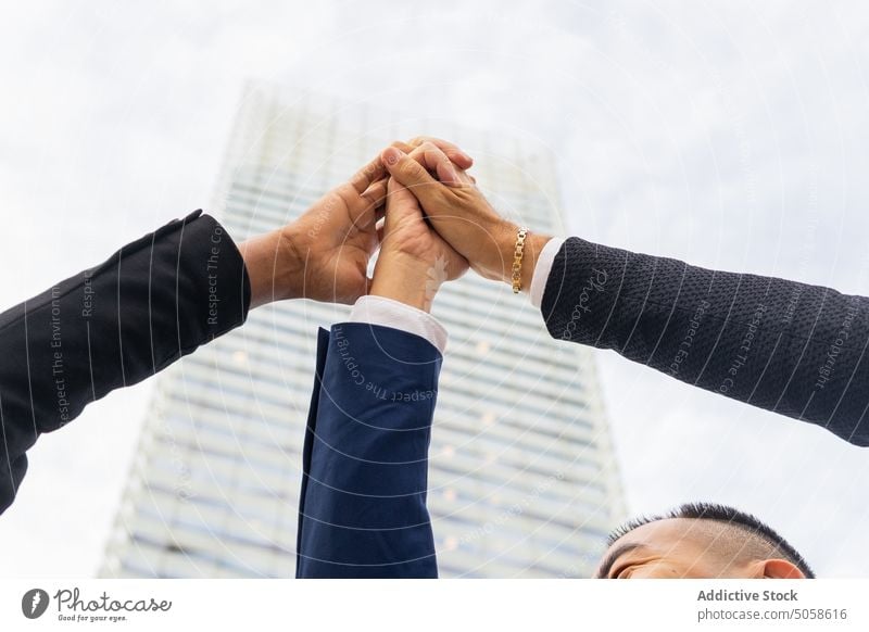 Anonymous businesspeople stacking raised hands on street coworker colleague stack hands arms raised skyscraper team collaborate cooperate partner success