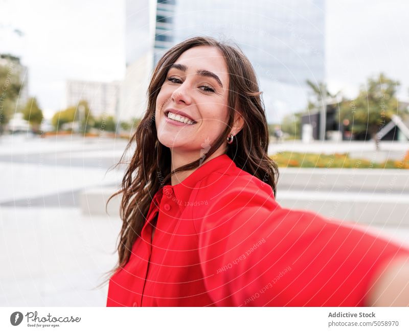 Happy stylish female taking selfie on street woman smile happy urban style brown hair young long hair cellphone self portrait carefree glad memory daytime