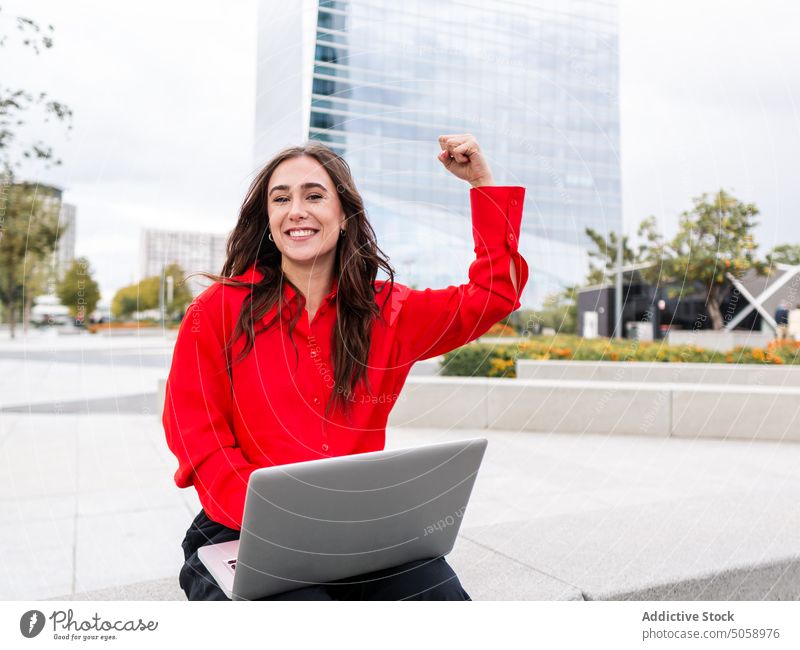 Female freelancer with laptop showing bicep woman using street smile happy project park female young power device gadget cheerful business glad positive content