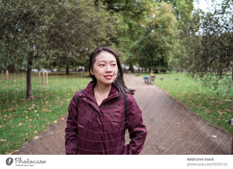 Asian woman standing in park autumn weekend lawn city admire casual wait london england united kingdom uk female young asian ethnic outerwear daytime season