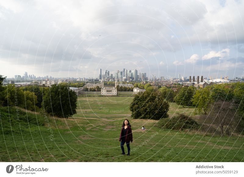 Female traveler in field near city woman grass building cloudy sky summer tree london greenwich england united kingdom uk royal observatory female overcast