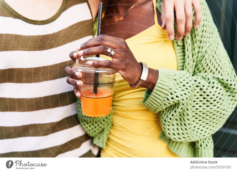 Crop anonymous multiracial couple embracing on city street cuddle drink takeaway relationship together juice love close spend time beverage boyfriend girlfriend