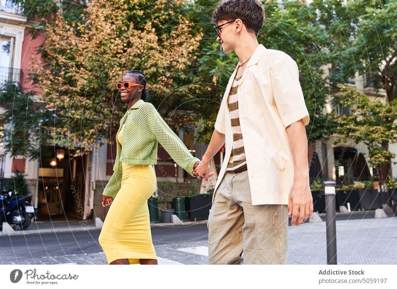 Stylish diverse couple holding hands and walking on street crosswalk city together cool love style confident relationship road boyfriend girlfriend young