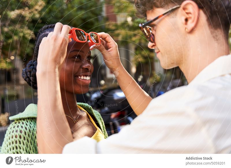 Loving ethnic man adjusting sunglasses of smiling girlfriend on street couple smile relationship love positive style romantic happy together city cheerful young