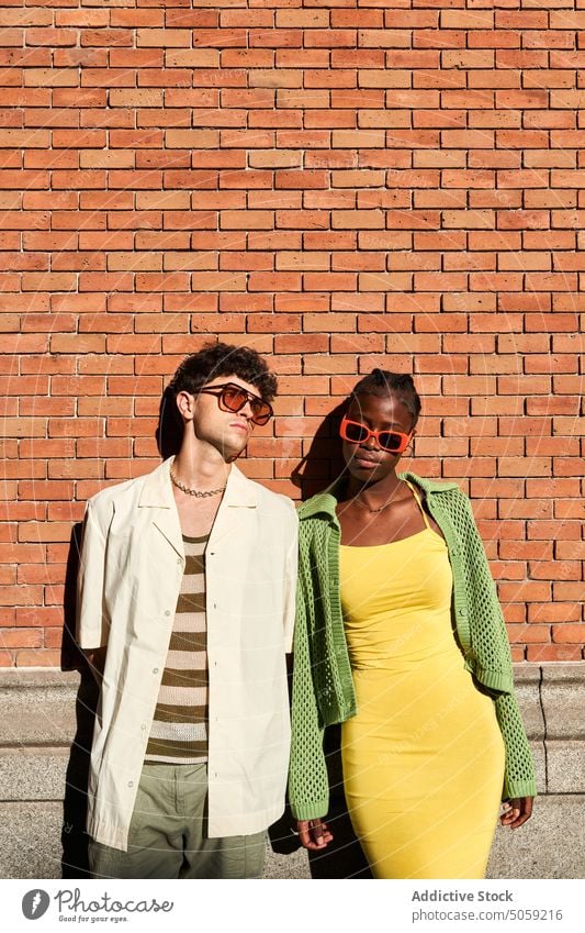 Stylish diverse couple looking away on street in daylight spend time relationship trendy style glamour together soulmate partner wall summer gorgeous sunglasses