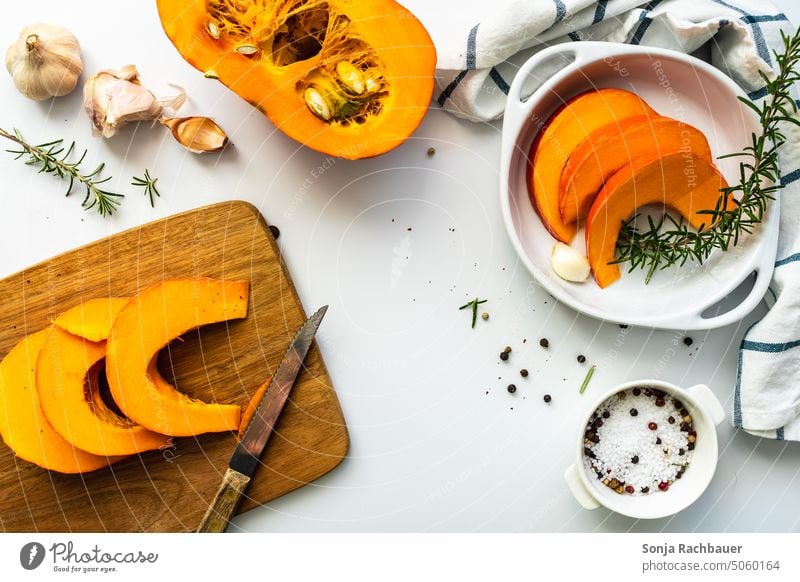 Hokkaido pumpkin sliced on a cutting board and ingredients on a white table Pumpkin Vegetable Autumn Organic produce Raw Food Orange Fresh Thanksgiving Healthy