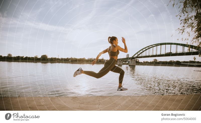 Active young beautiful woman running on the promenade along the riverside active activity athlete athletic city endurance exercise female fitness healthy jogger