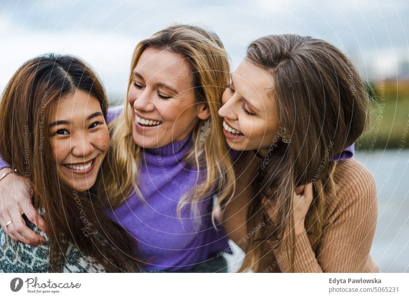 Three female friends hugging each other real people candid woman girls young adult friendship girlfriends girl power fun city urban city life youth millennials