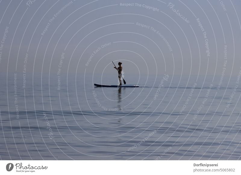 Woman with stand up board SUP board on the sea SEA supboard stand-up paddling Ocean Paddle Boating trip boat Stand Blue Baltic Sea Horizon Water Sports hobby