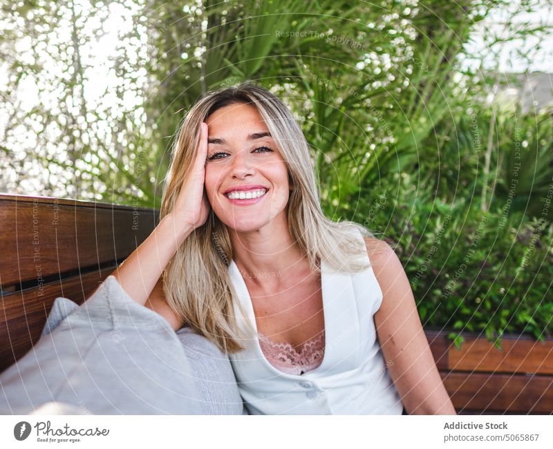 Thoughtful female sitting on terrace woman lean on hand cheerful summer blond bored happy weekend daytime young adult contemplate glad individuality personality