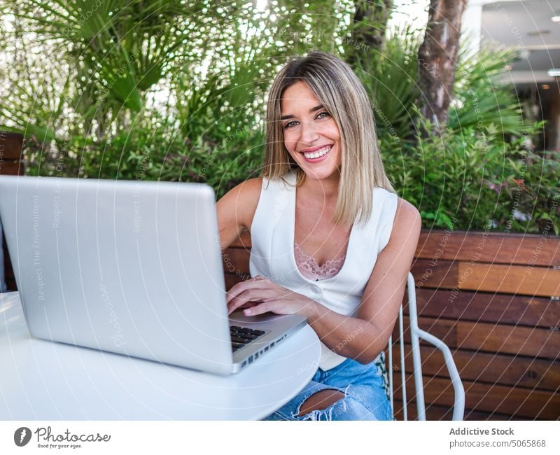 Cheerful female freelancer using laptop on terrace woman smile remote summer project online young blond surfing happy connection browsing internet job positive