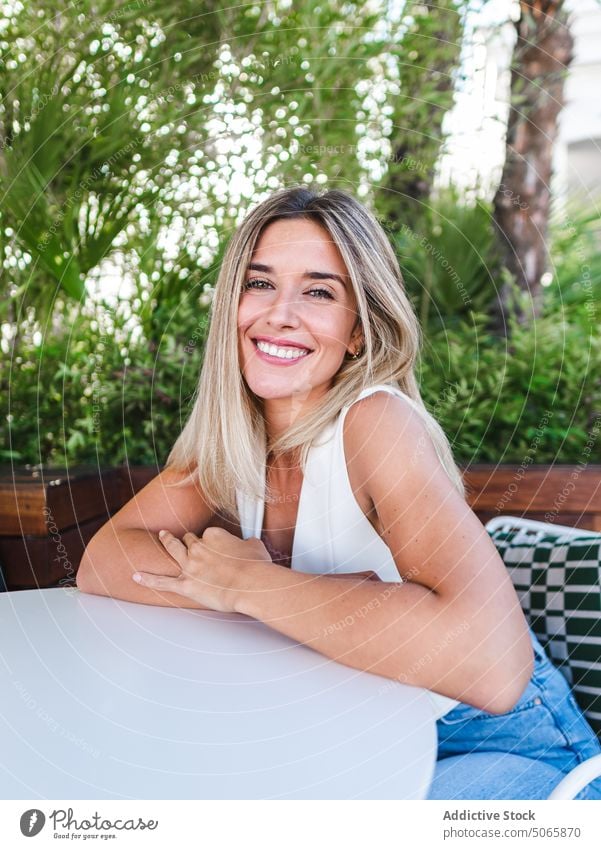 Thoughtful female sitting on terrace woman lean on hand cheerful summer blond bored happy weekend daytime young adult contemplate glad individuality personality