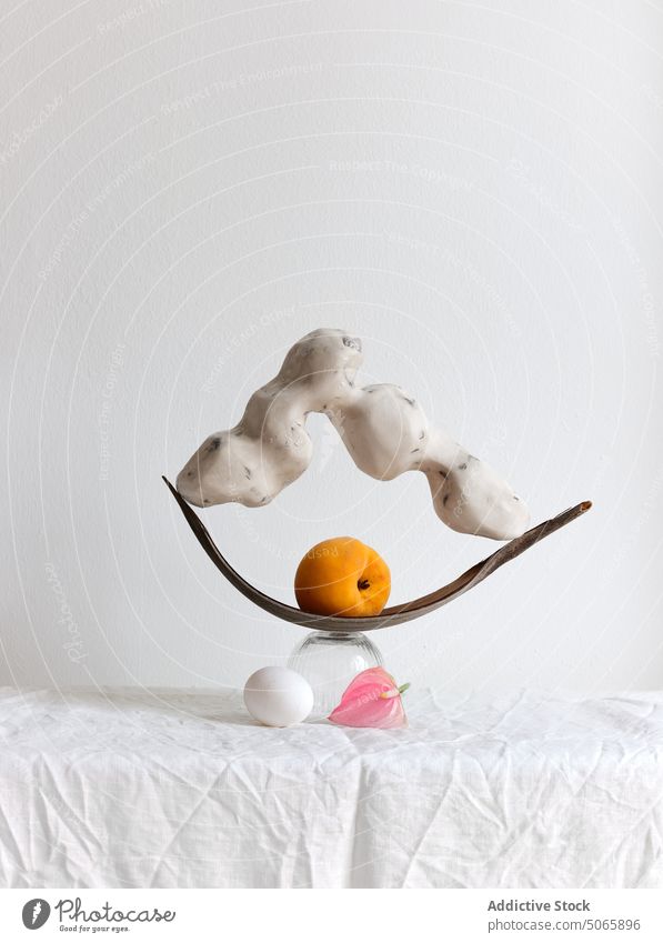 Arrangement with handmade sculpture and a peach still life design fruit shape egg glass stone ceramic object texture fabric textile wrinkles balance arrangement