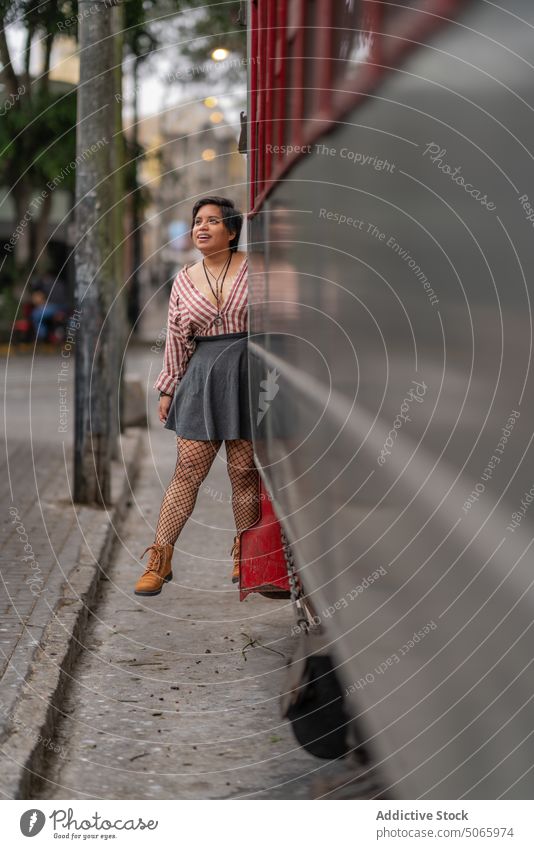 Happy ethnic female tourist standing on traditional tram steps woman traveler style passenger commute smile tramway city positive street young peruvian