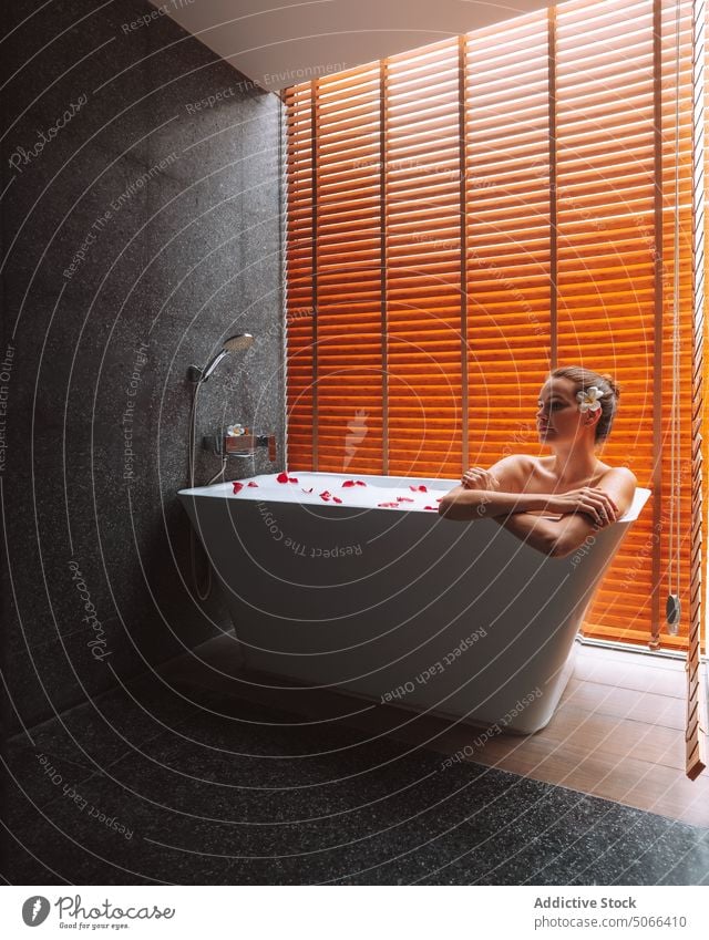 Woman resting in tub with petals woman bathtub resort chill flower relax spa bathroom foam wellness calm treat pamper pleasure hygiene comfort weekend bubble