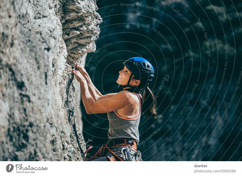 Woman climbing a rock with extreme effort in a vertical rock wall active activity adventure andalusia athletic austrian cliff climber committed endurance