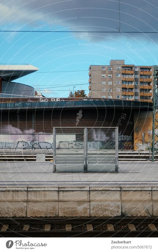 Railroad track, platform, waiting bench, in the background residential houses as urban ensemble Track Railway track Platform Train station Bench Waiting bench